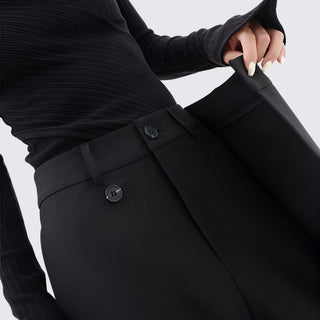 Person wearing black pants with a belt on a light gray background