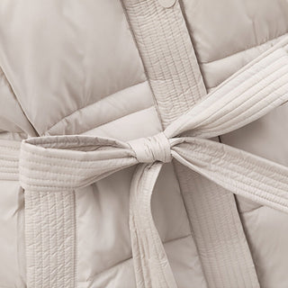 Close-up of a beige quilted jacket with a tie belt