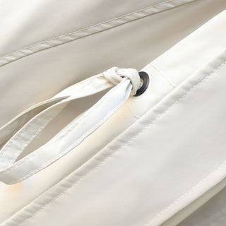 Close-up of a beige fabric with a white strap and black button detail.