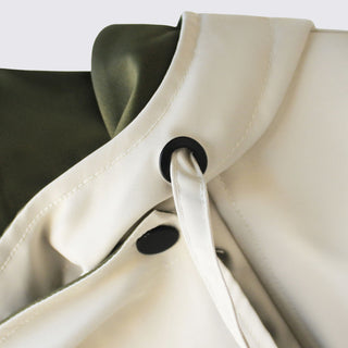 Close-up of a beige garment with black buttons on a white background