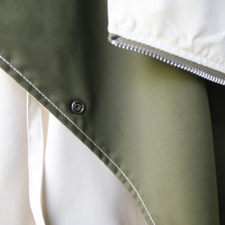 Close-up of a green fabric corner with a button on a white background