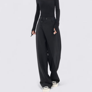 Person wearing black high-waisted pants on a light gray background