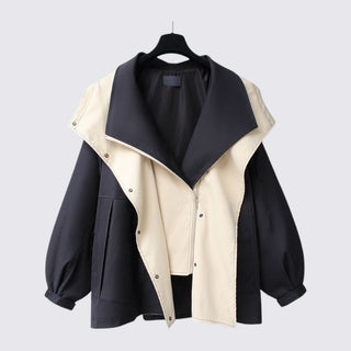 Two-tone black and beige jacket on a hanger against a light gray background