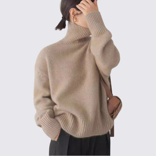 Person wearing a beige turtleneck sweater on a light gray background
