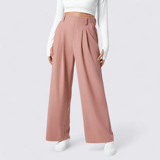 Pink wide-leg pants worn with a white top and shoes on a light gray background