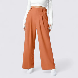 Orange wide-leg pants worn with a white top and shoes on a light gray background