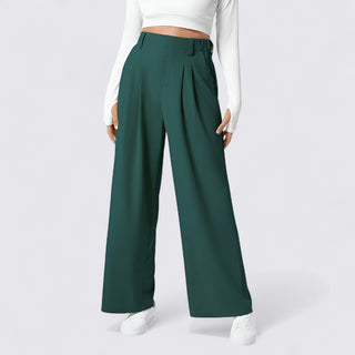 Green wide-leg pants worn with a white top on a plain background
