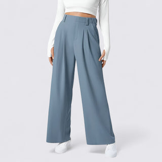 Blue wide-leg pants worn with a white top and shoes on a light gray background