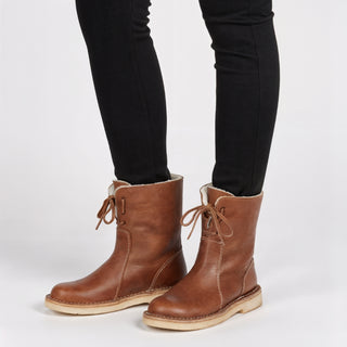 Brown leather boots worn with black pants on a white background